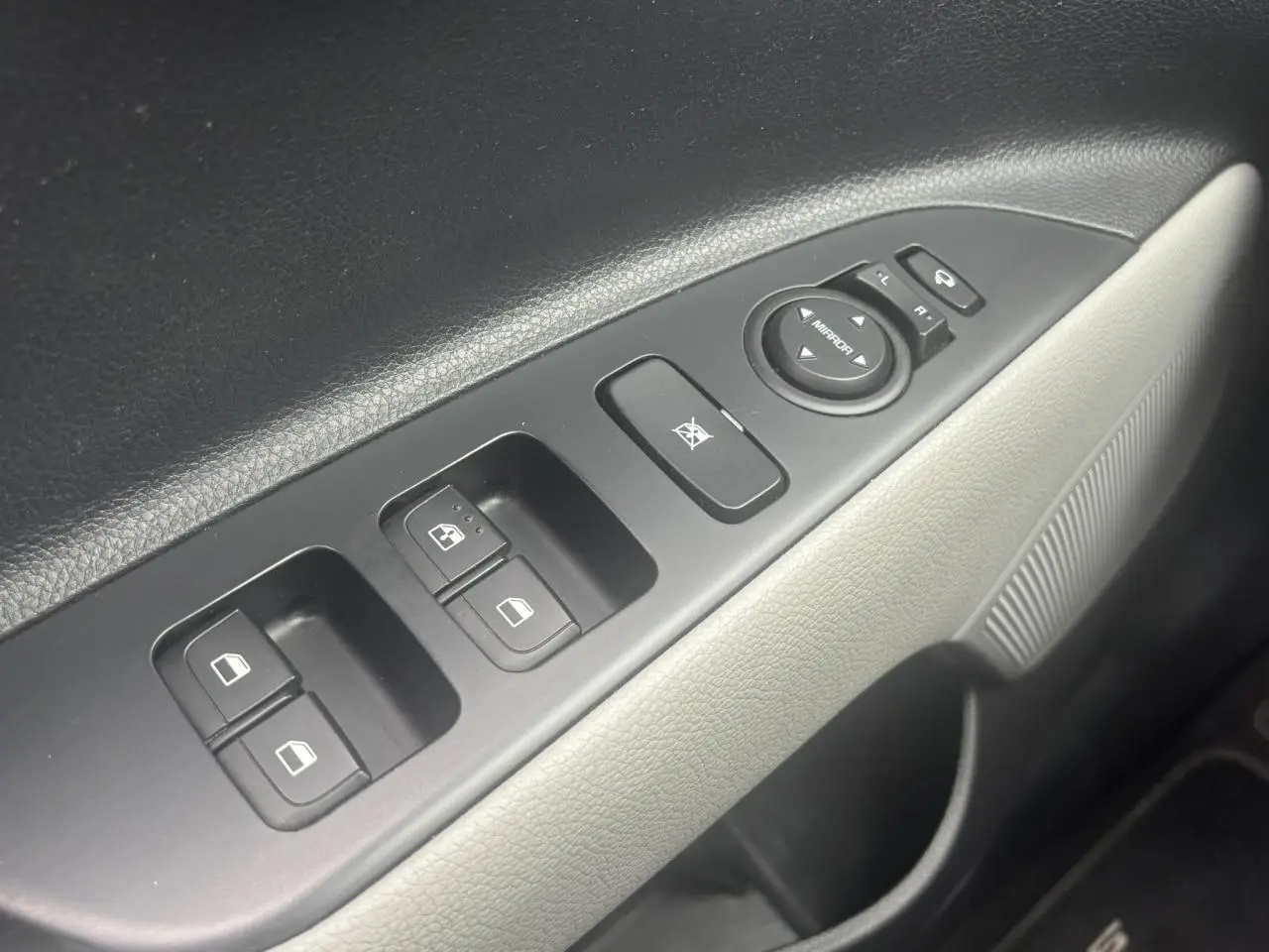 Gros plan sur la commande des vitres électriques côté conducteur du Kia Stonic rouge, avec réglage des rétroviseurs.