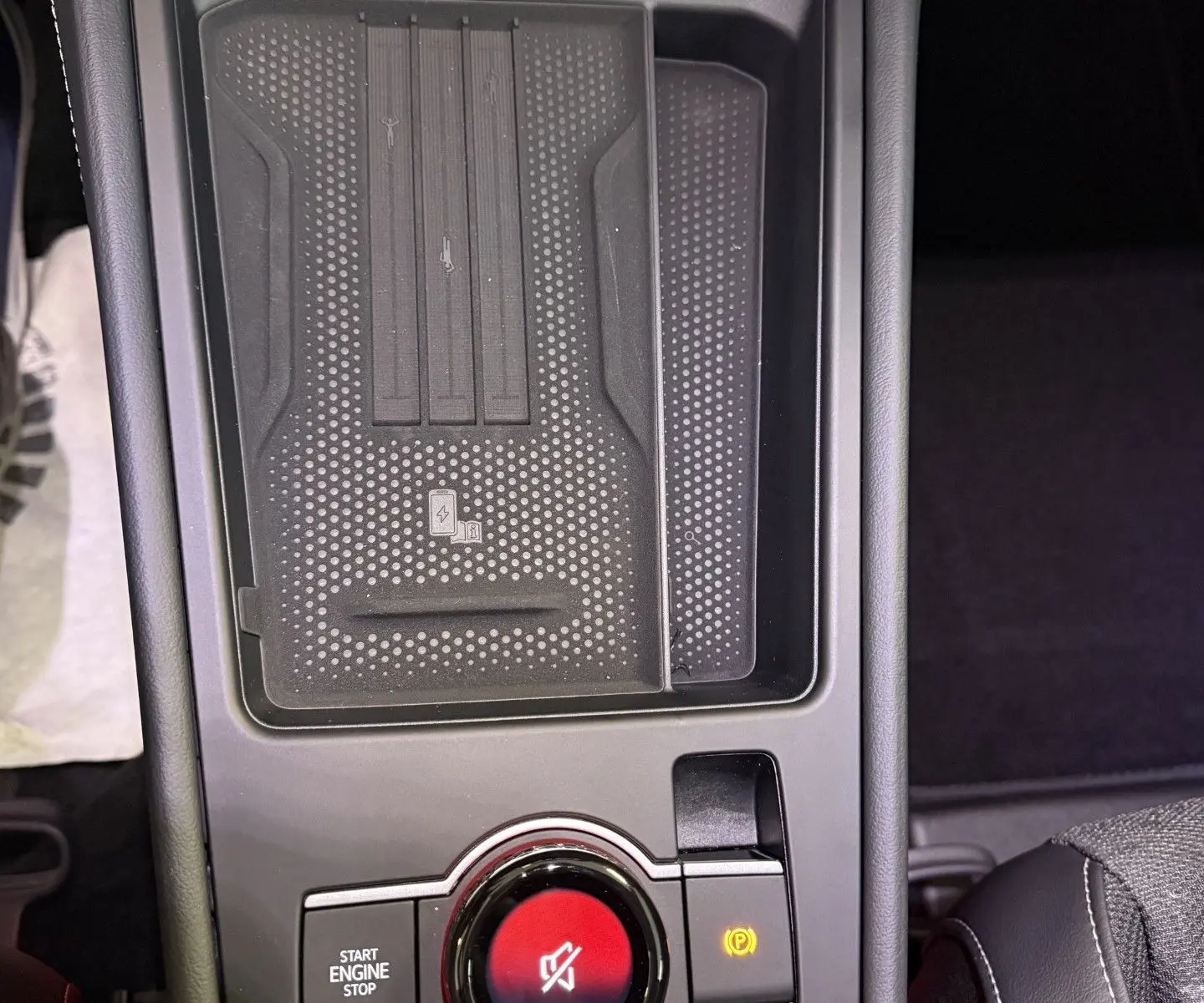 Vue rapprochée de la console centrale noire du Volkswagen T-Roc 2026, avec bouton rotatif et zone de recharge sans fil.