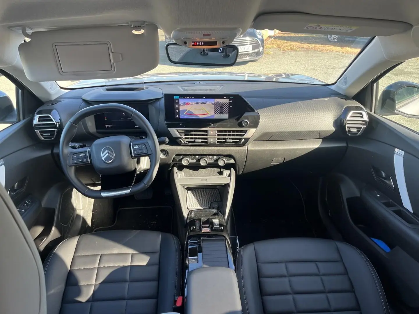 Vue intérieure avant de la Citroën C4 X 2025, tableau de bord moderne avec écran tactile et sièges cuir noirs.