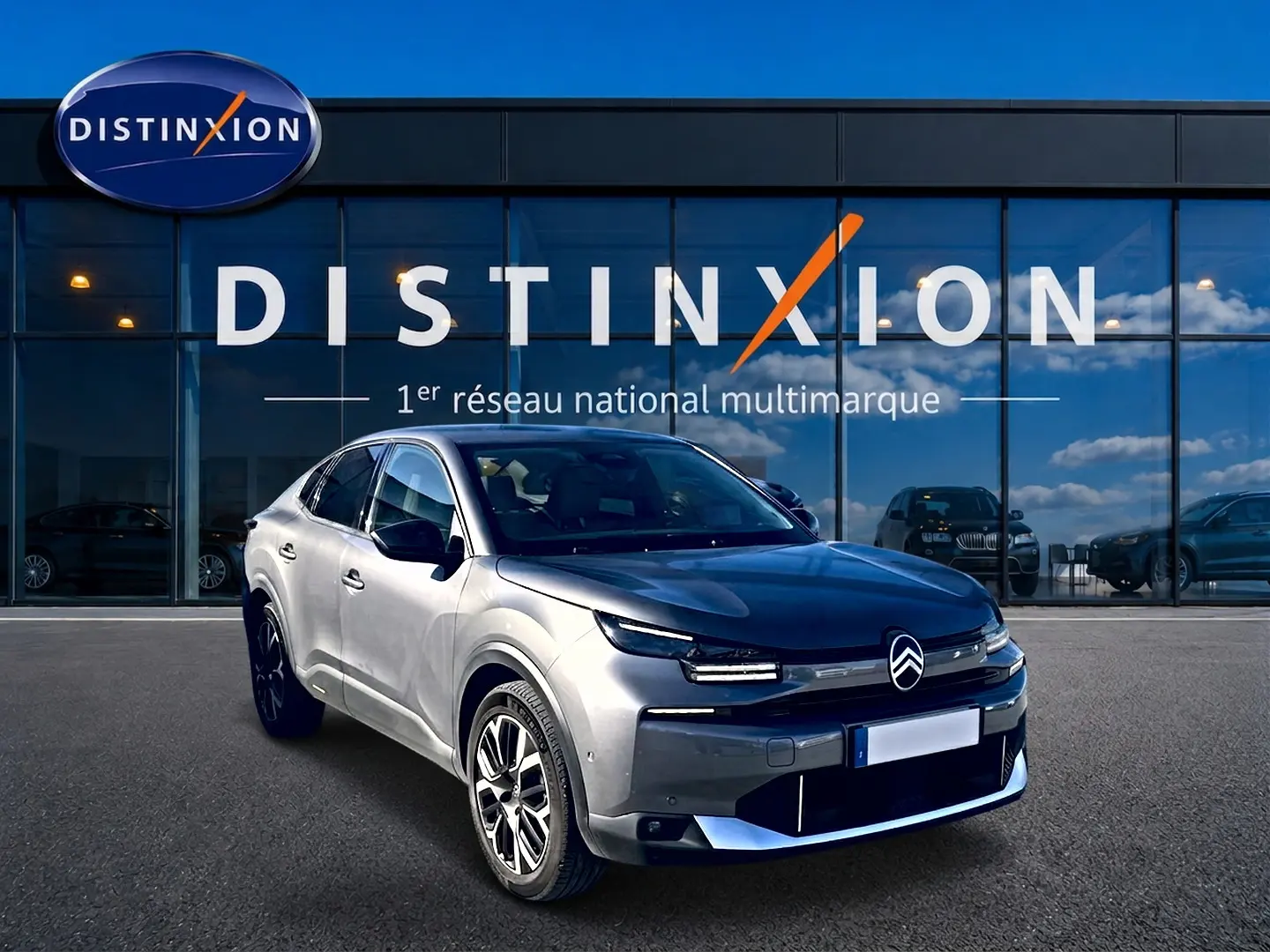 Vue 3/4 avant droit d'une Citroën C4 X gris mercure devant une vitrine avec logo Distinxion.