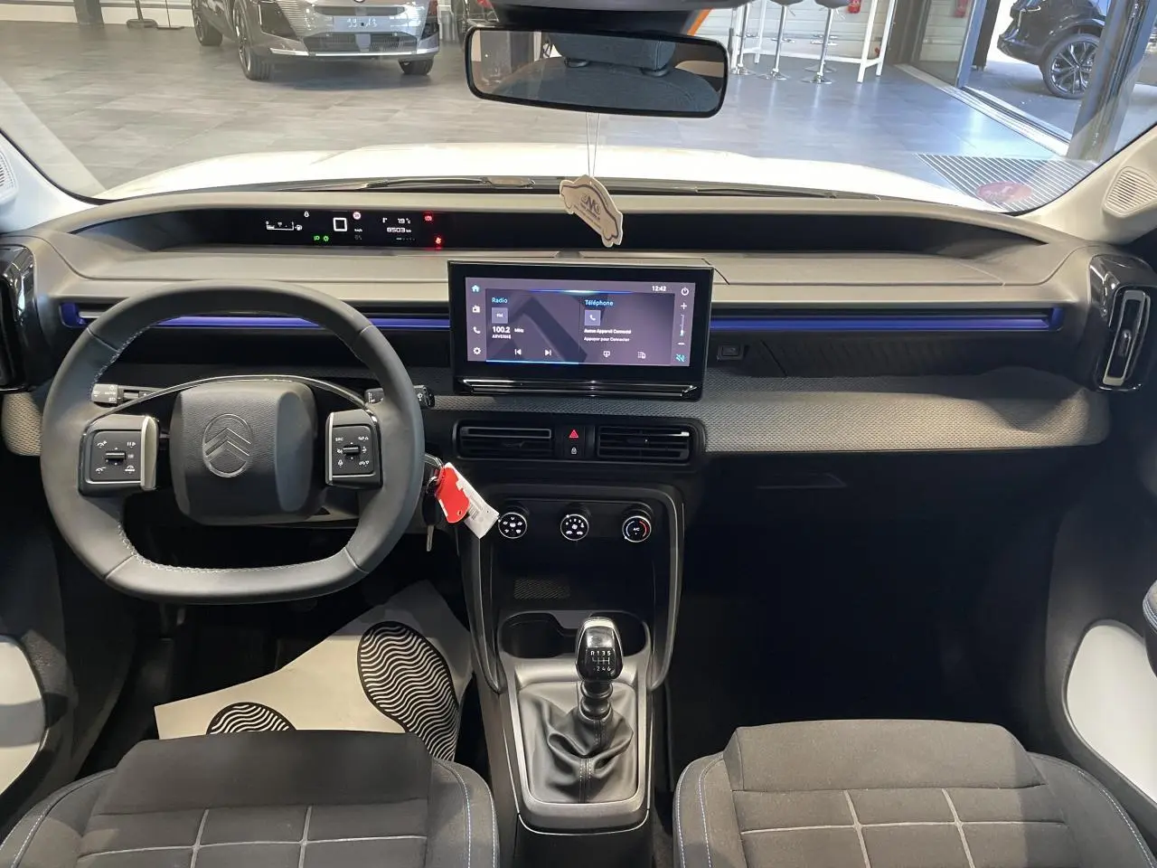 Vue intérieure avant de la Citroën C3 blanche 2025, tableau de bord avec écran tactile et volant multifonctions.