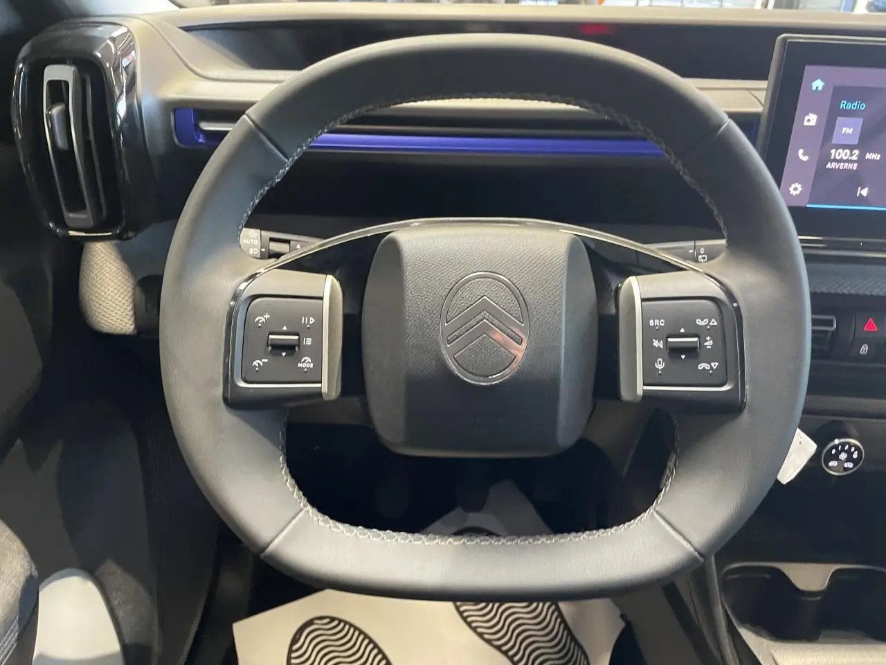 Vue rapprochée du volant cuir noir de la Citroën C3 2025 avec commandes intégrées et tableau de bord moderne.