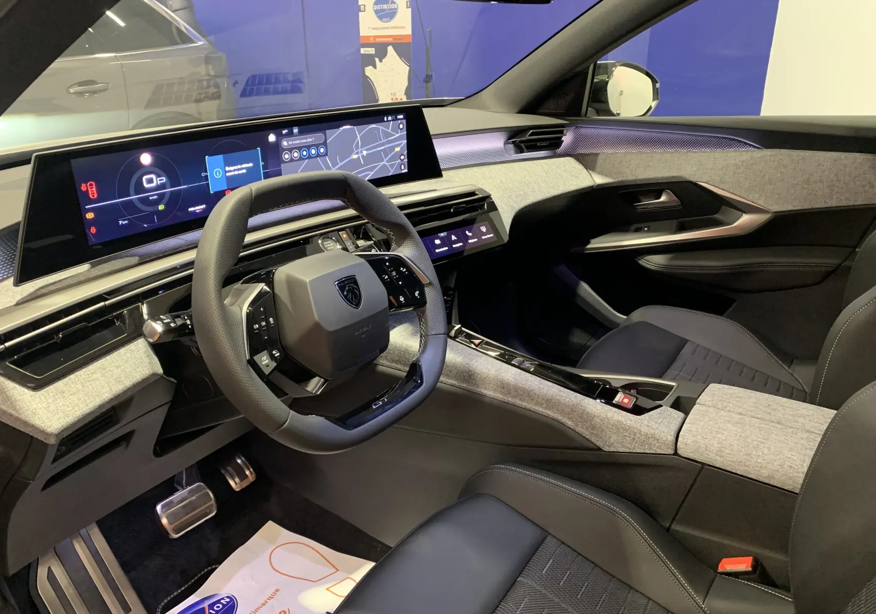 Vue intérieure côté conducteur du Peugeot 3008 III GT HYBRID 136 e-DSC6 2025 avec tableau de bord numérique et finitions tissu et cuir.