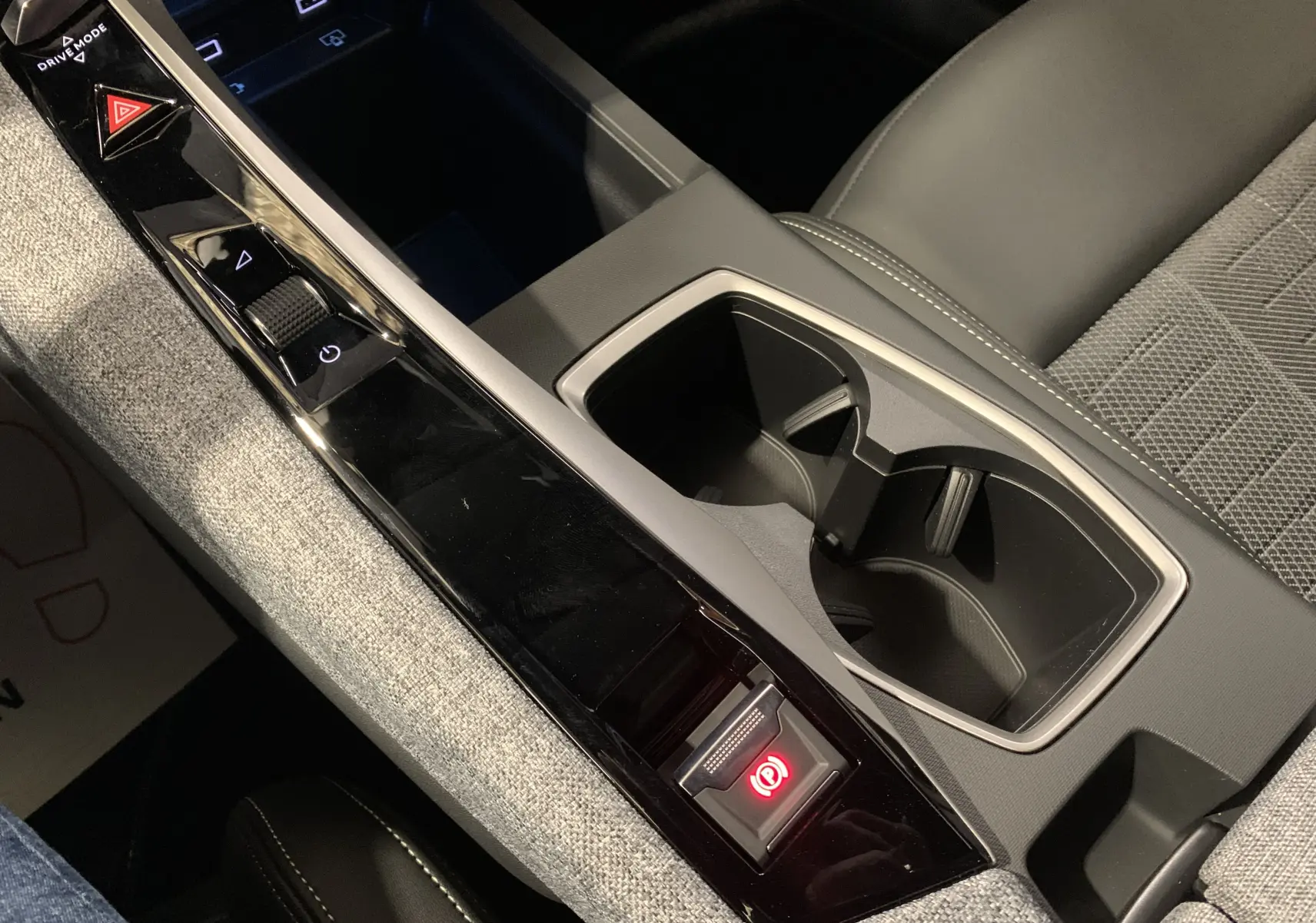 Vue rapprochée de la console centrale du Peugeot 3008 III GT HYBRID 136 e-DSC6 2025 gris Artense, avec commandes et porte-gobelets.