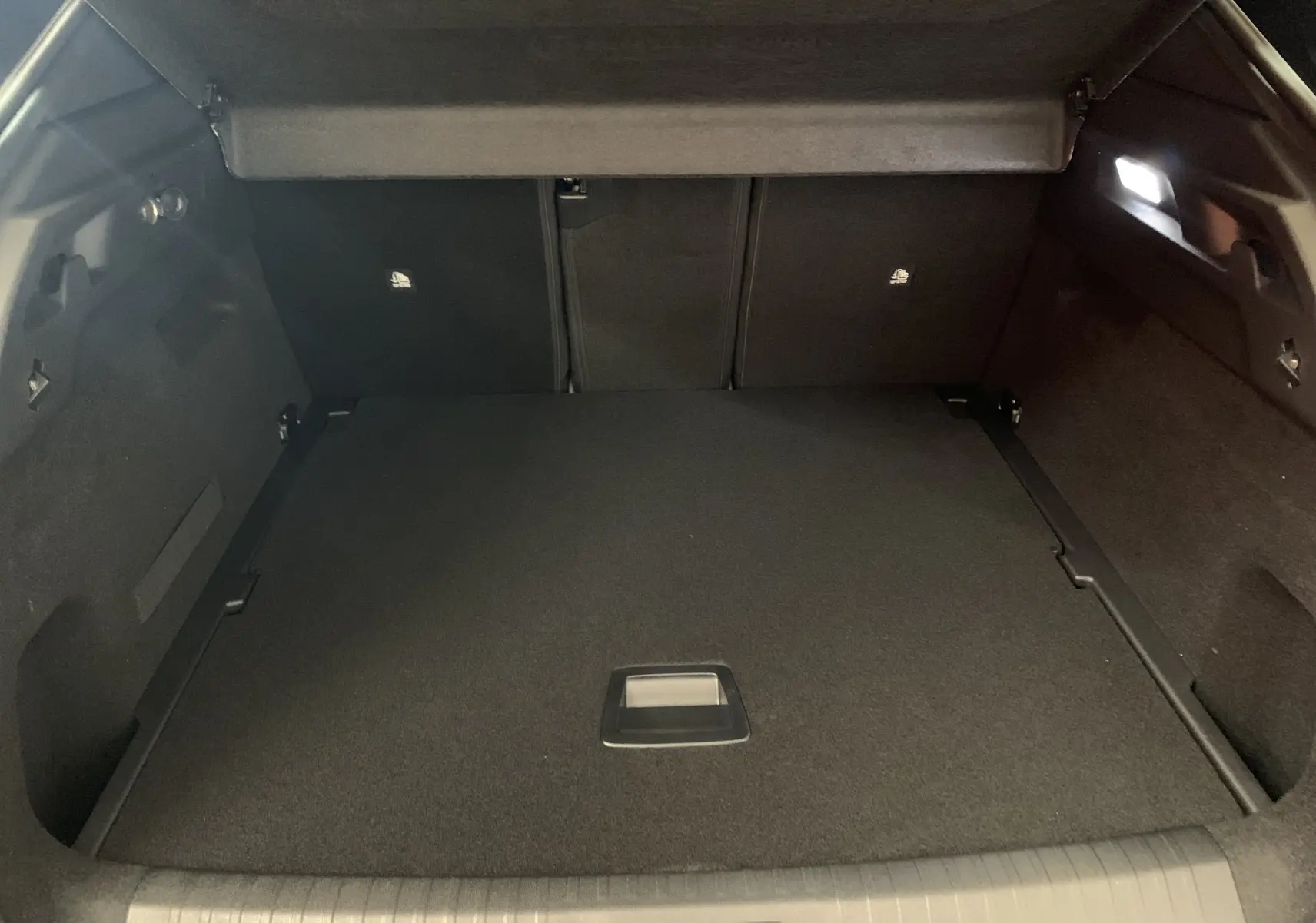 Coffre spacieux et noir du Peugeot 3008 III GT Hybrid 136 e-DSC6 vu de l'arrière avec cache-bagages relevé.