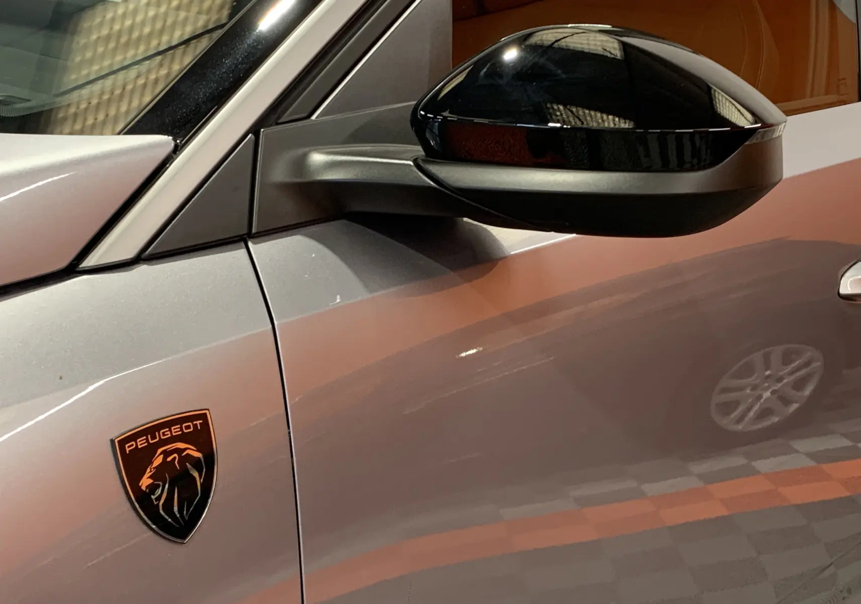 Gros plan sur le rétroviseur noir et l’écusson Peugeot sur la porte gris Artense du 3008 III GT Hybrid 2025 côté gauche.