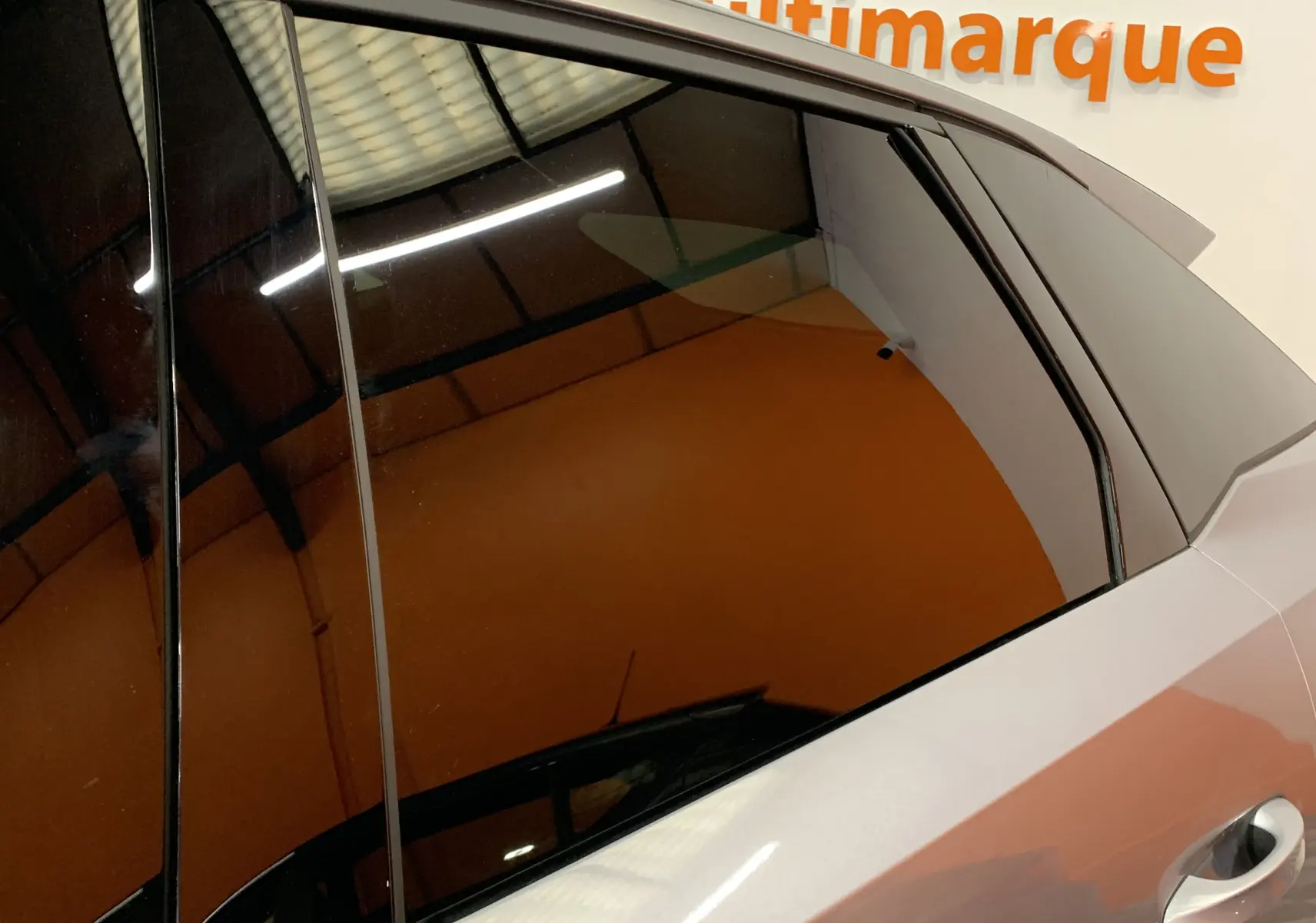 Gros plan sur la vitre arrière côté droit du Peugeot 3008 III GT Hybrid 136 e-DSC6 gris Artense avec reflet intérieur.