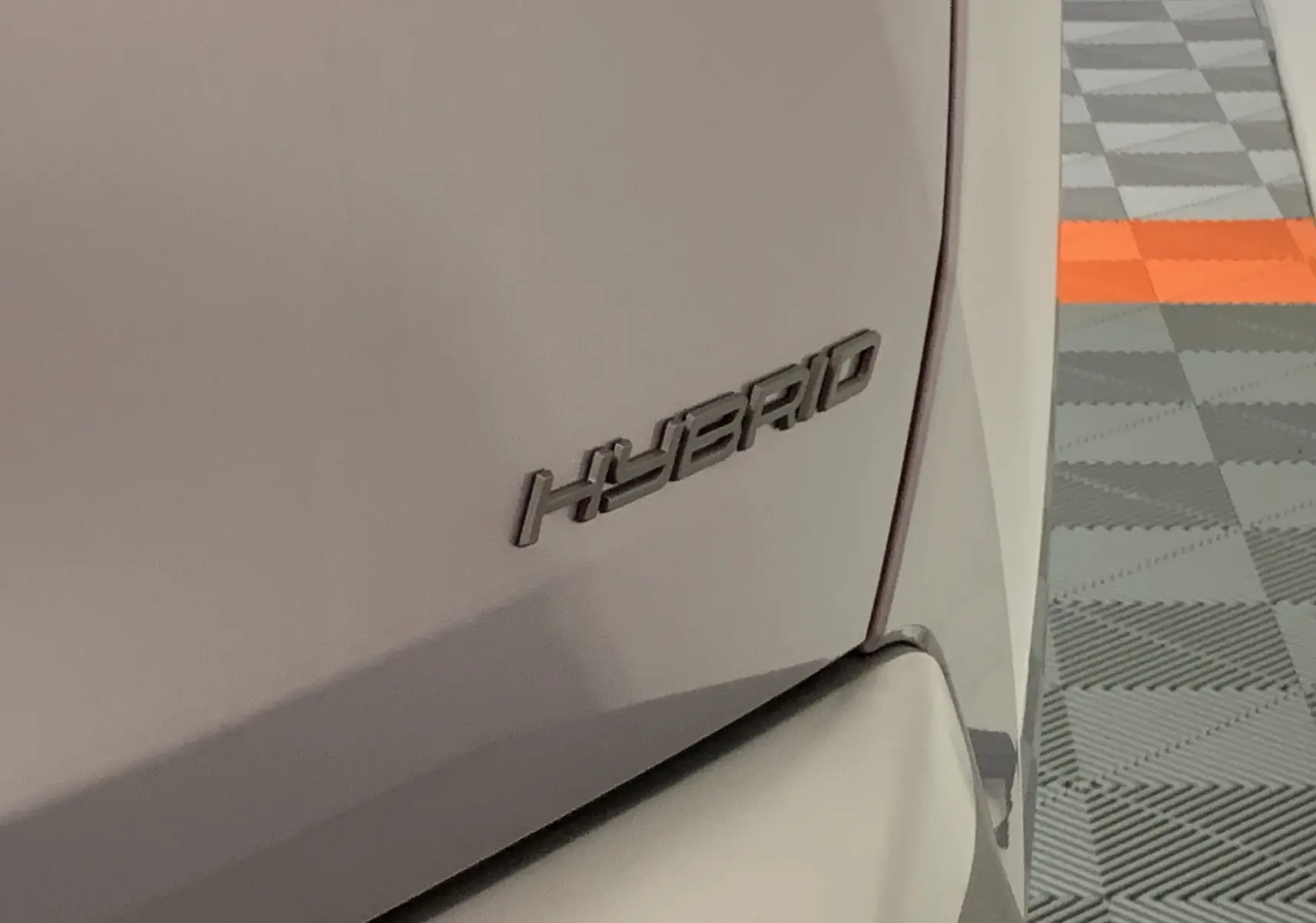 Gros plan sur l’inscription Hybrid à l’arrière droit du Peugeot 3008 gris Artense 2025 en intérieur.
