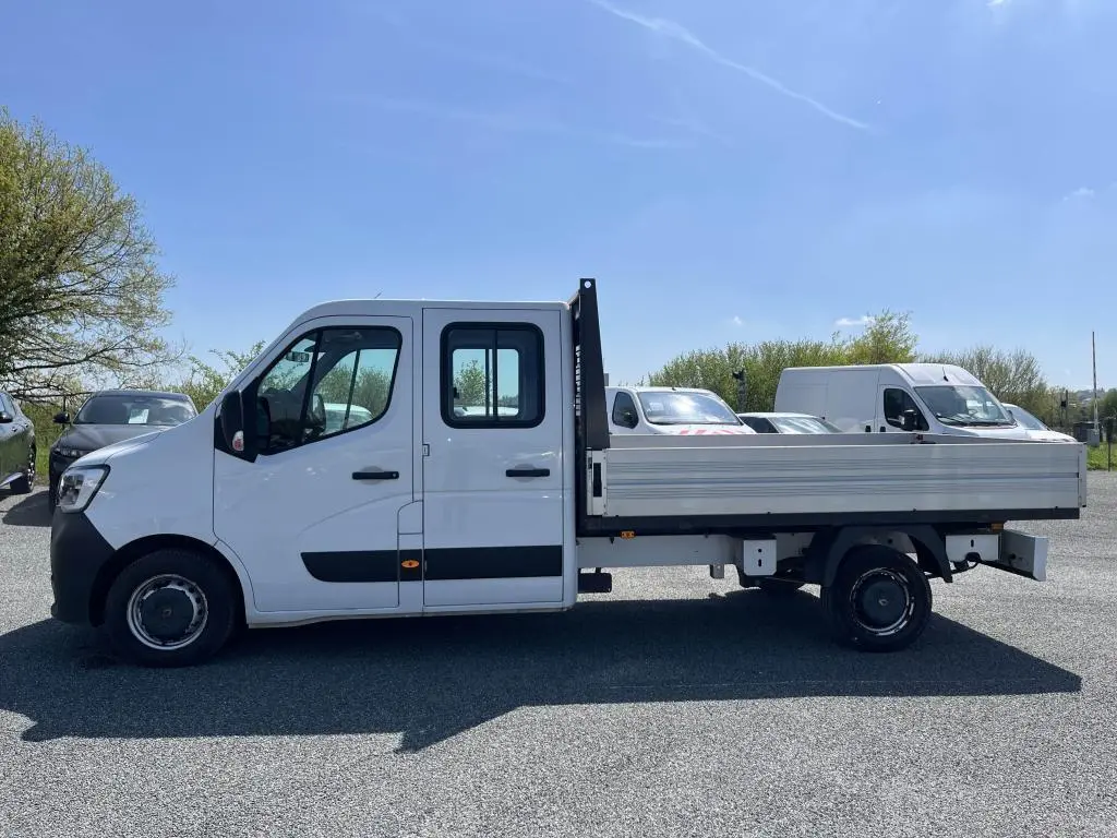 Profil droit d'un Renault Master blanc version Grand Confort avec plateau ridelles aluminium et double cabine visible.
