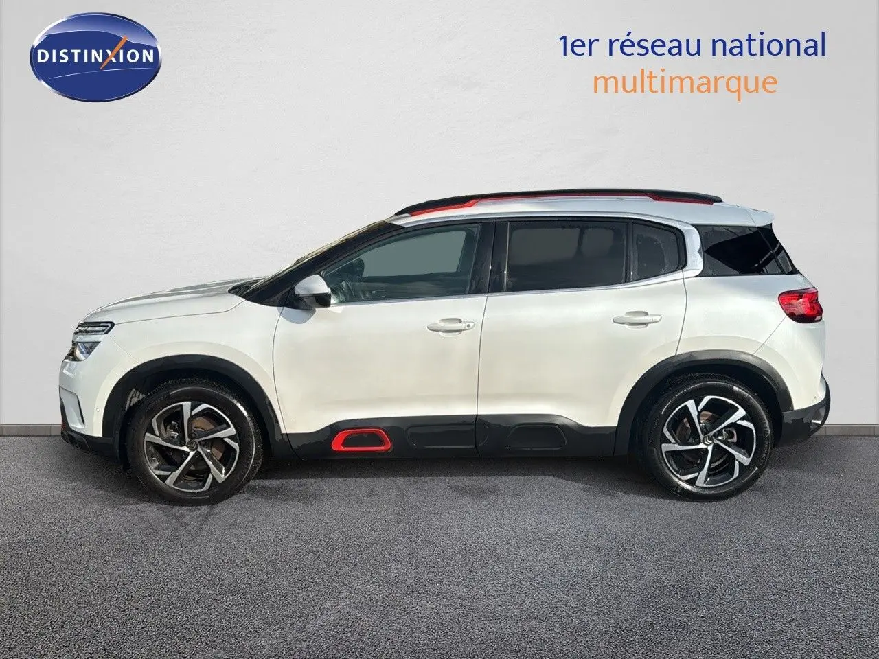 Profil côté gauche d'un Citroën C5 Aircross blanc nacré avec inserts rouges et jantes alliage distinctives.