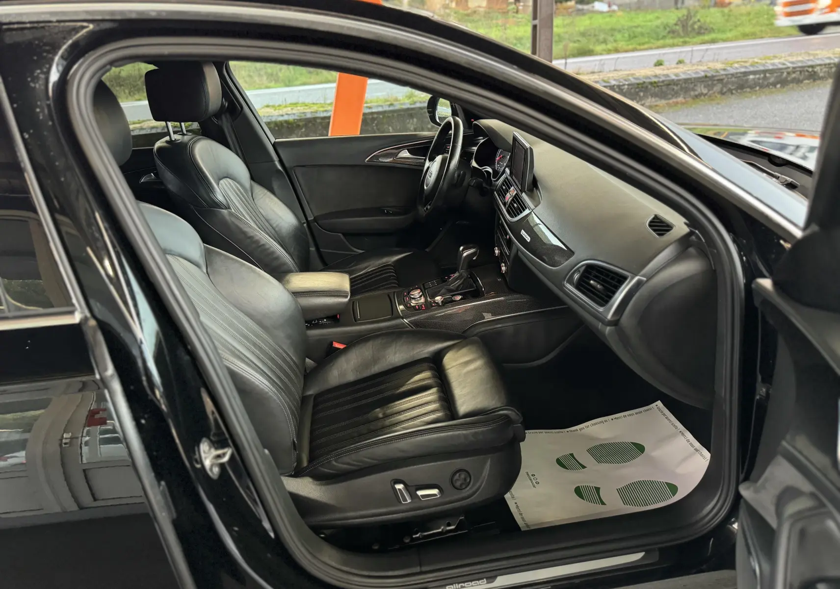 Vue intérieure côté conducteur d'une Audi A6 Avant Allroad noire de 2016, avec sièges cuir noir et tableau de bord moderne.
