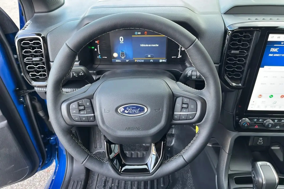 Vue rapprochée du volant cuir multifonctions et tableau de bord numérique du Ford Ranger bleu lightning 2025.