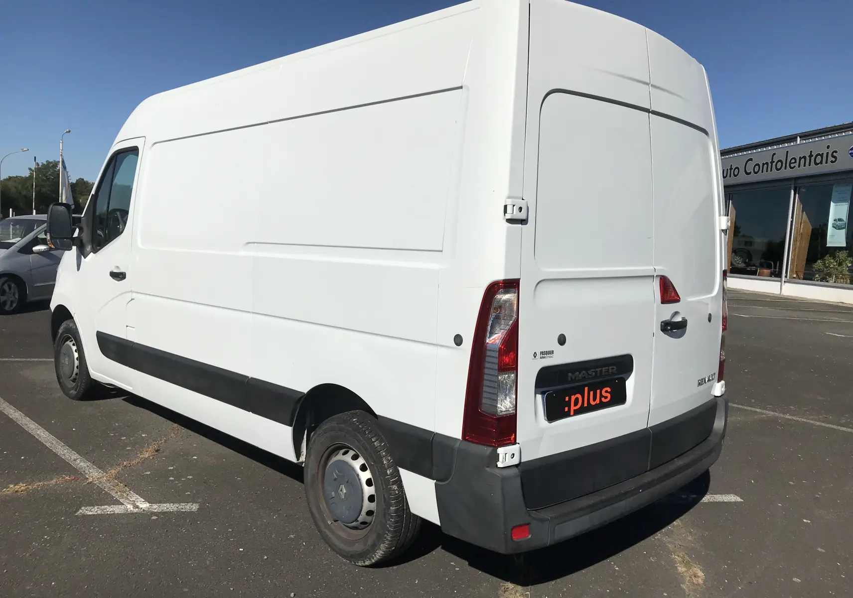 Vue 3/4 arrière droite d'un utilitaire Renault Master blanc avec porte arrière fermée sur un parking.