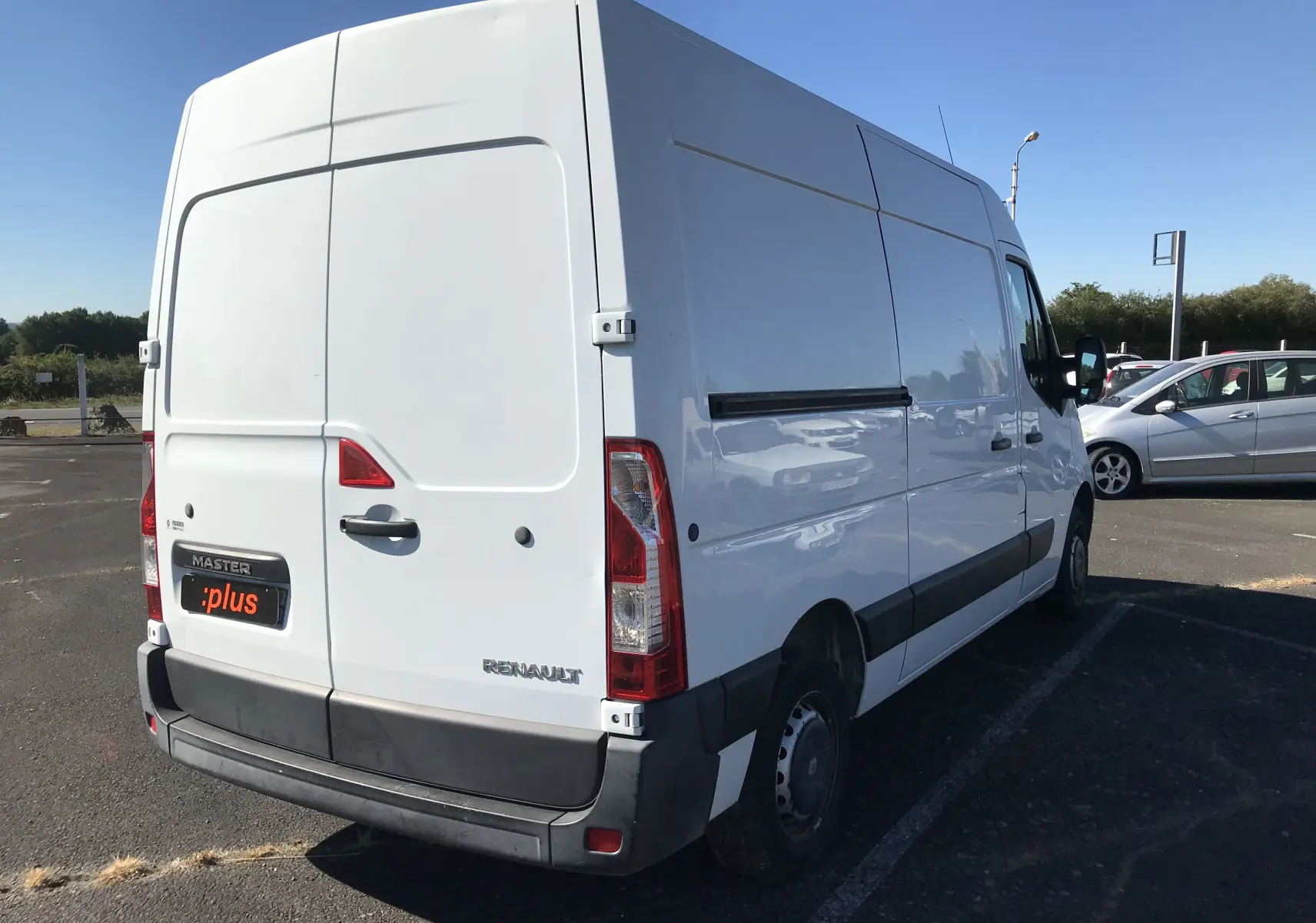 Renault Master blanc vu en 3/4 arrière droit, fourgon utilitaire avec porte arrière et pare-chocs noirs.
