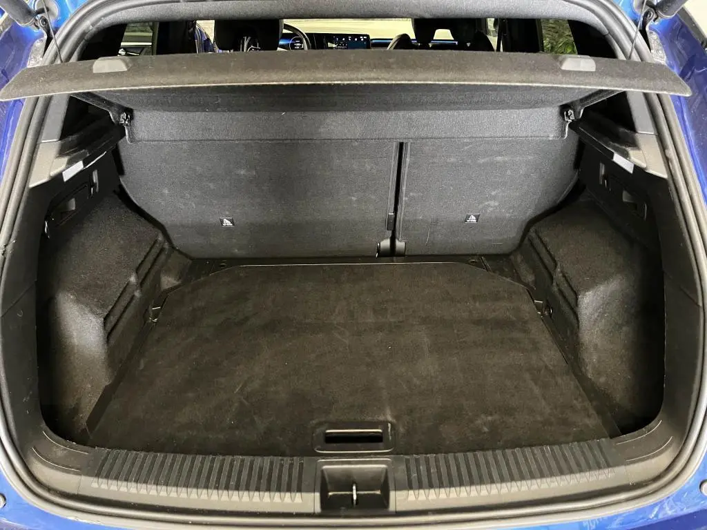 Coffre ouvert vu de l'arrière d'un Renault Austral bleu, montrant l'espace de chargement et la plage arrière.
