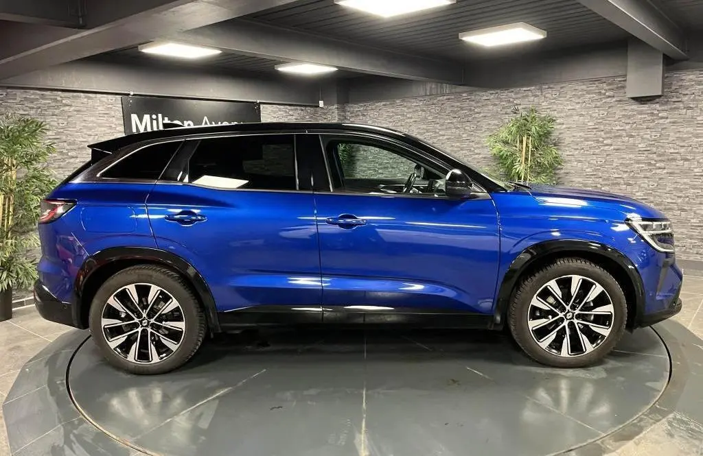 Profil côté gauche d'un Renault Austral bleu avec toit noir étoilé et jantes alliage 19 pouces Komah diamantées.