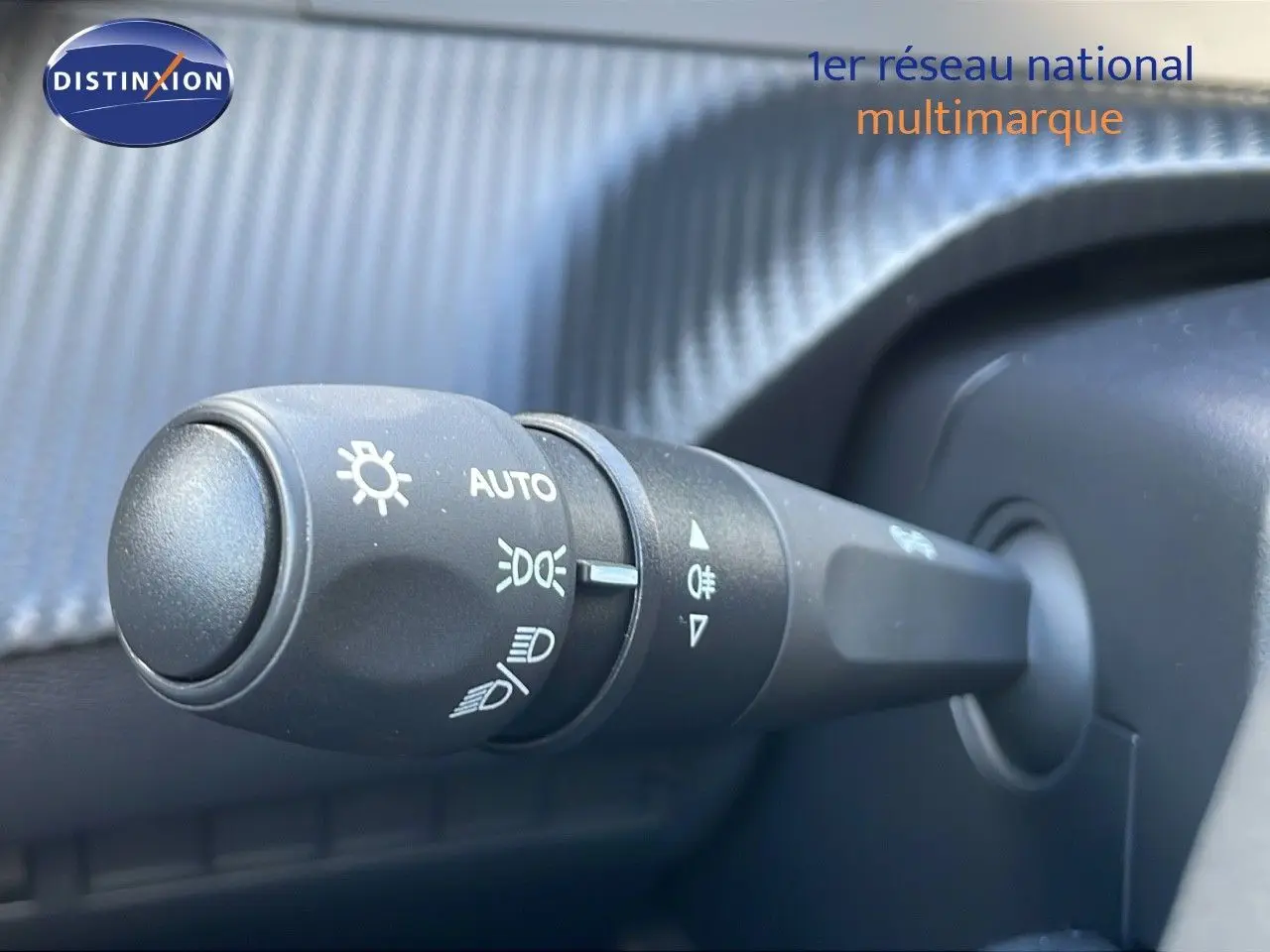 Gros plan sur la manette de commande des phares du Peugeot 2008 gris Artense, intérieur moderne et texturé.