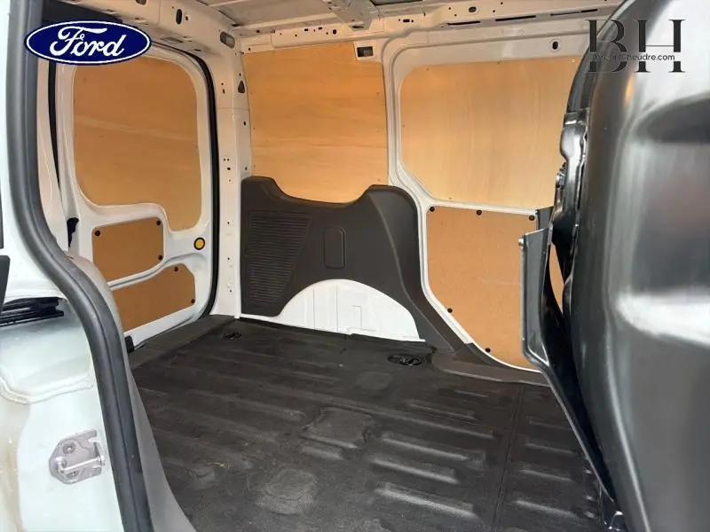 Vue intérieure arrière du Ford Transit Connect blanc glacier, montrant la zone de chargement avec cloison tôlée et plancher caoutchouc.