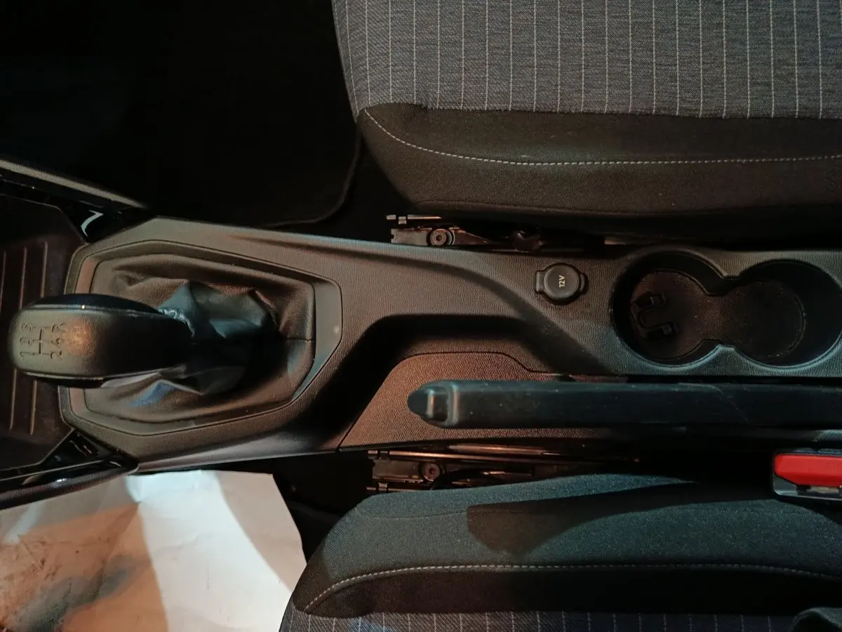 Vue plongeante sur la console centrale d'une Peugeot 208 noire, montrant levier de vitesses manuel et frein à main.