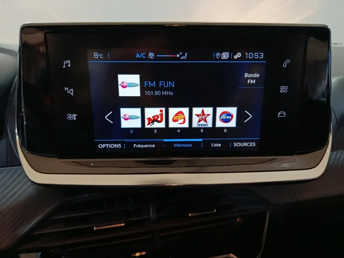 Écran tactile central de la Peugeot 208 2022 affichant les stations radio FM, avec cadre noir brillant.