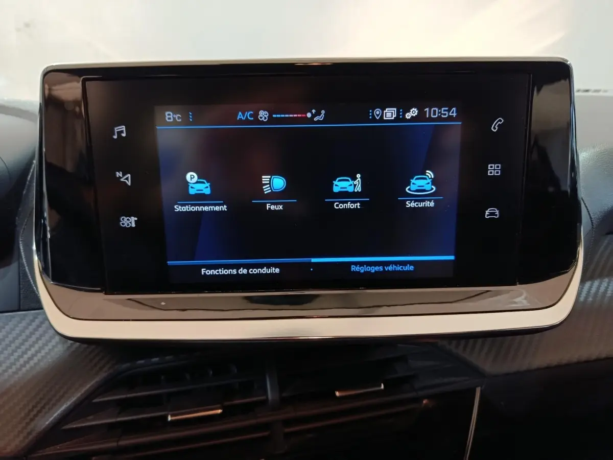 Écran tactile central du tableau de bord de la Peugeot 208 noire, affichant les réglages de conduite et sécurité.
