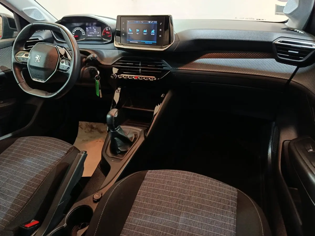 Intérieur Peugeot 208 2022 vu côté conducteur, tableau de bord avec écran tactile et volant compact noir.