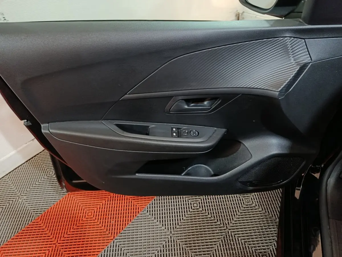 Vue rapprochée de la porte avant gauche noire d’une Peugeot 208 2022 avec commandes de vitres et miroir.