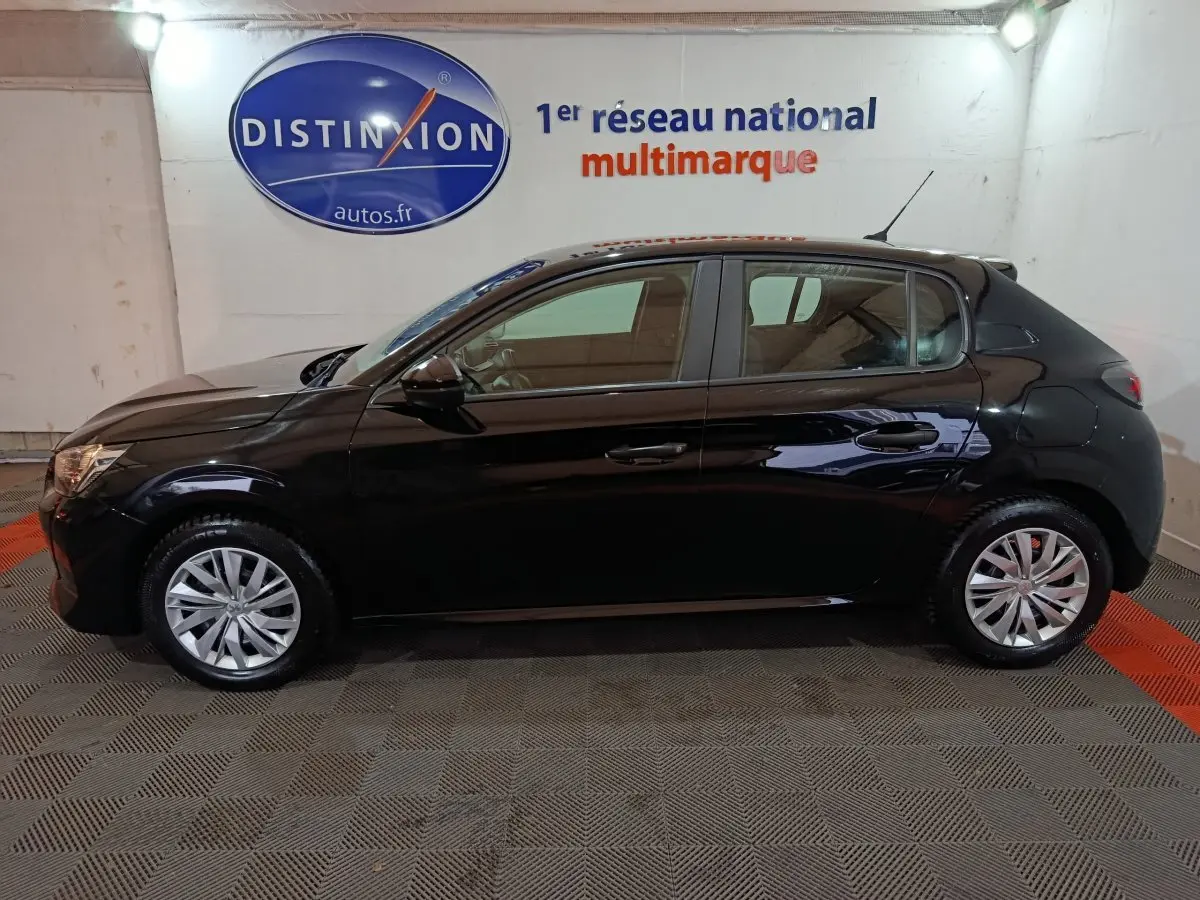 Vue latérale droite d'une Peugeot 208 noire 2022, compacte et brillante, stationnée en intérieur sur sol damier.