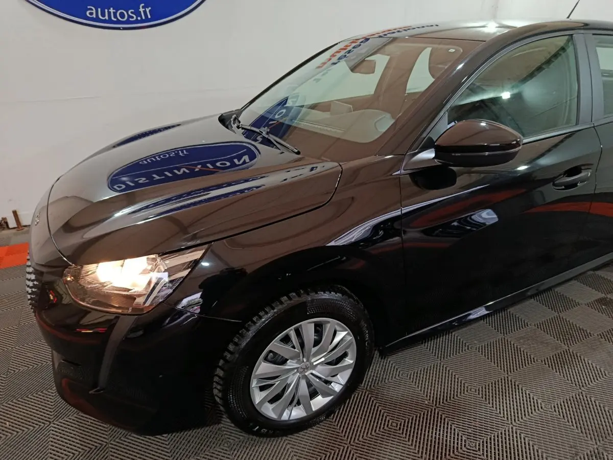 Vue 3/4 avant droit d'une Peugeot 208 noire 2022 avec phares allumés et jantes alliage visibles.