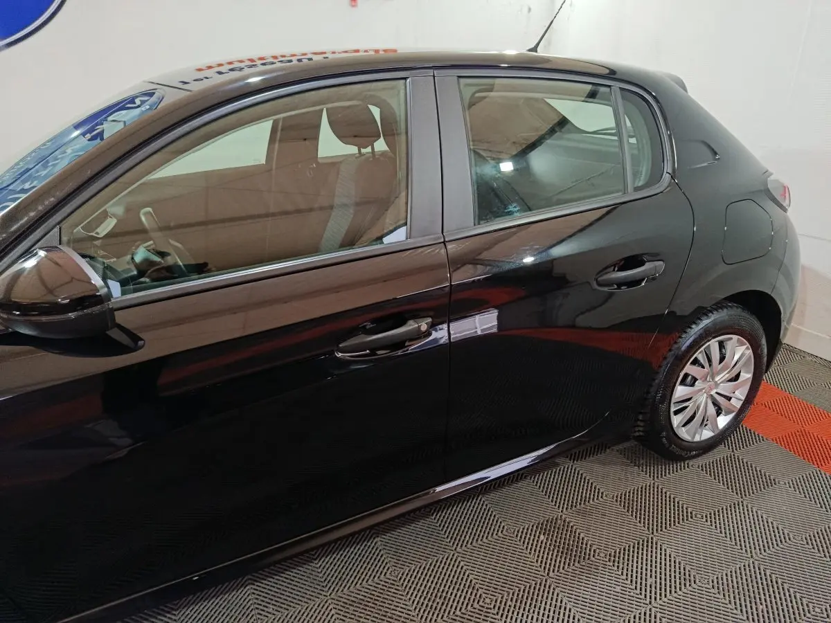 Vue latérale gauche d'une Peugeot 208 noire 2022, mettant en valeur les portières et les jantes en alliage.