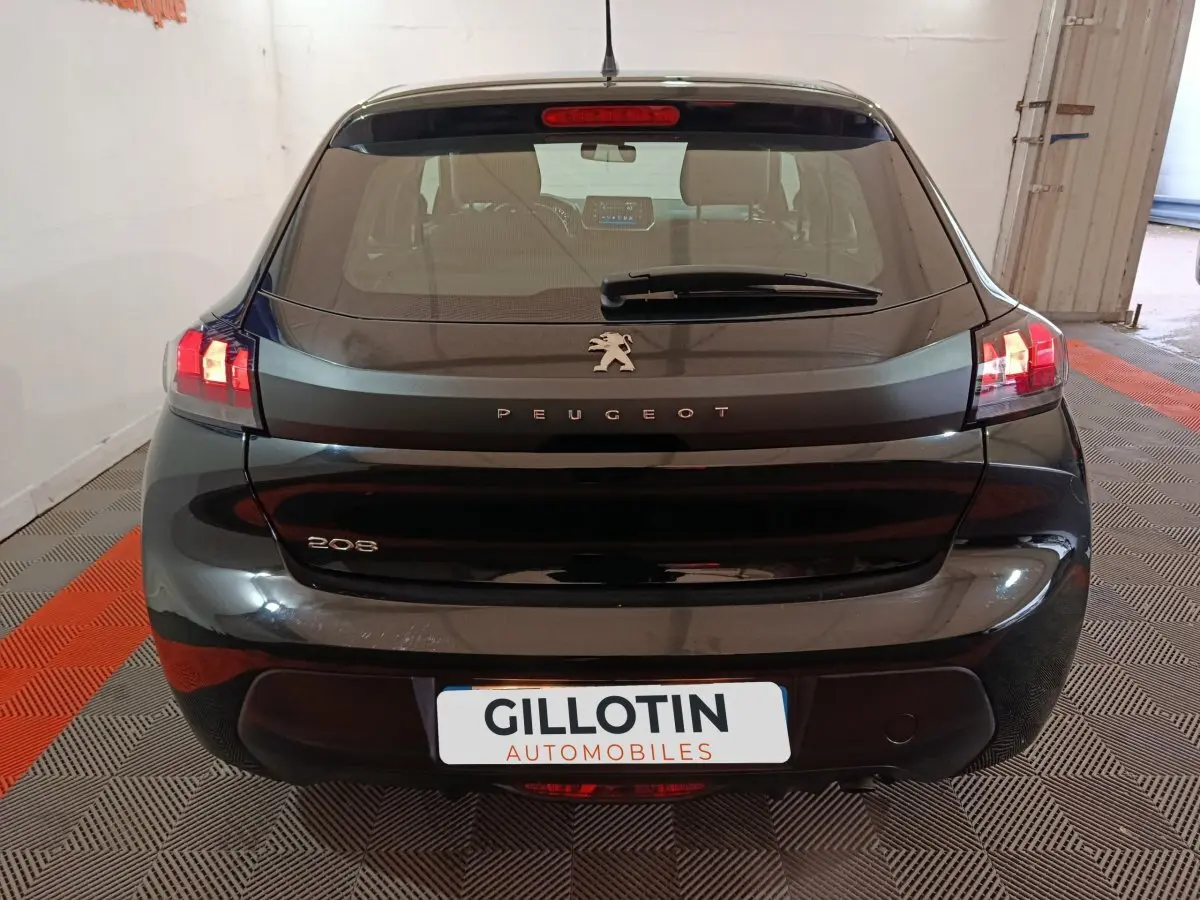 Vue arrière d'une Peugeot 208 noire 2022 avec feux LED allumés dans un garage intérieur.