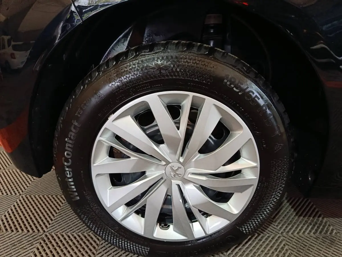 Gros plan sur la roue avant droite d'une Peugeot 208 noire de 2022 avec jante argentée et pneu hiver WinterContact.