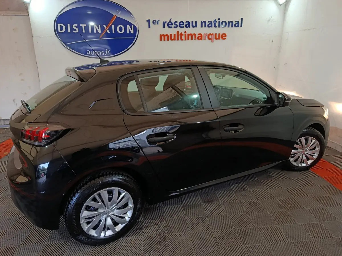 Peugeot 208 noire vue de profil côté droit dans un showroom avec jantes alliage et feux arrière LED.