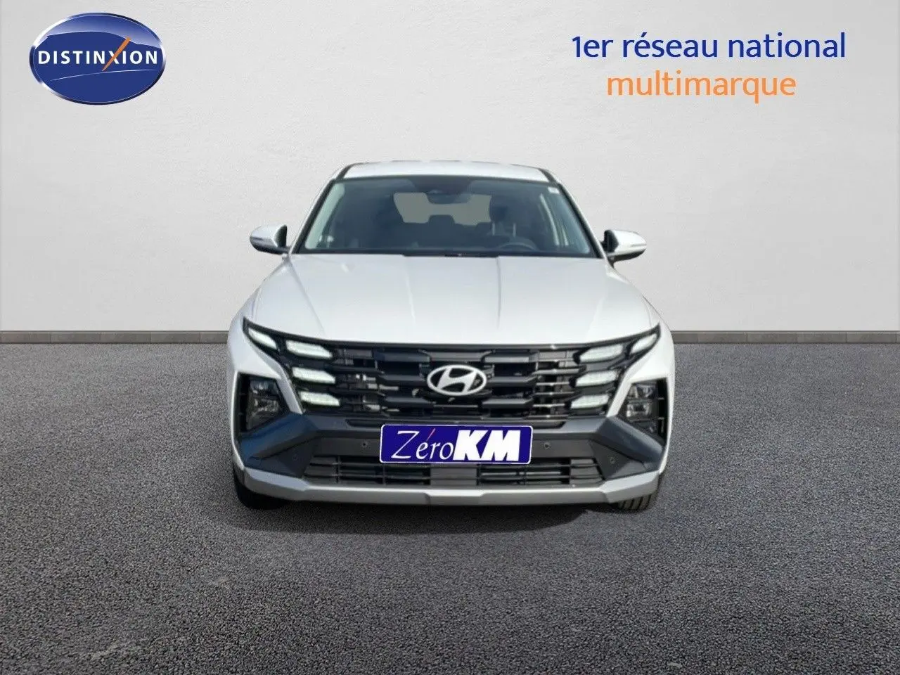 Vue frontale du Hyundai Tucson blanc Atlas 2026 avec calandre noire et feux LED distinctifs allumés.
