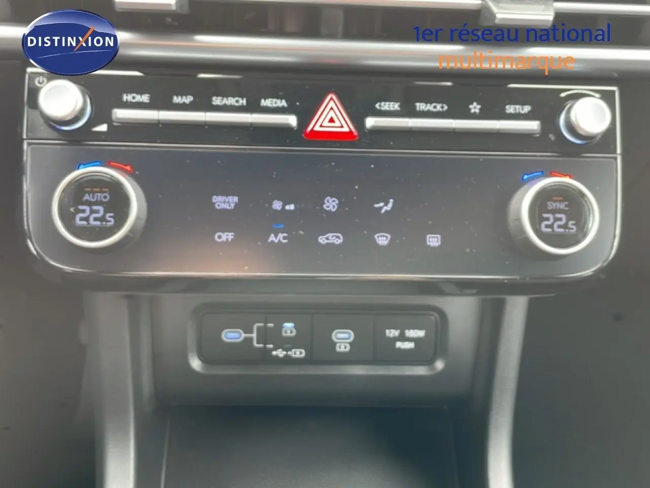 Vue rapprochée de la console centrale du Hyundai Tucson blanc, montrant les commandes de climatisation et les ports USB.