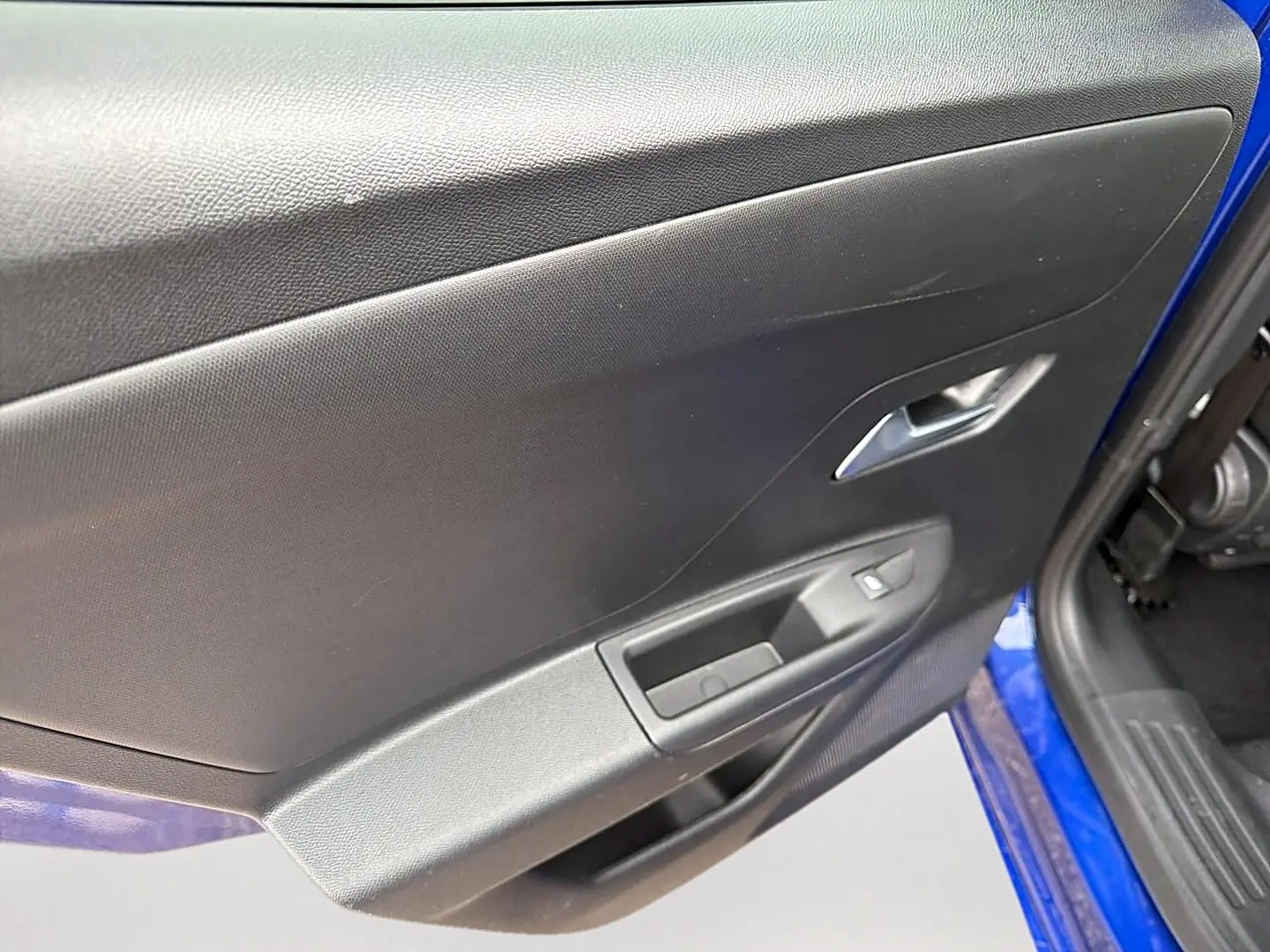 Vue rapprochée de la porte avant gauche noire avec commandes électriques sur un Opel Mokka bleu 2025.