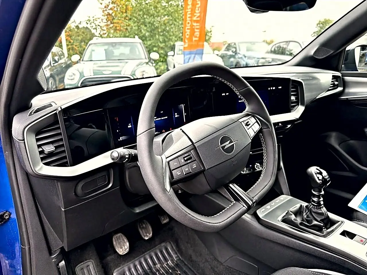 Vue intérieure côté conducteur de l’Opel Mokka bleu 2025, volant multifonction et levier de vitesse manuel visibles.