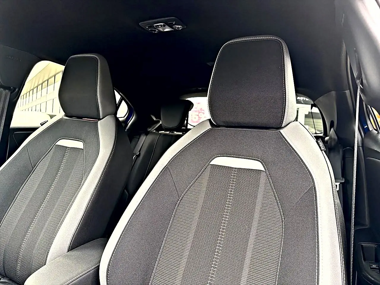 Vue intérieure montrant les sièges avant en tissu gris et noir de l’Opel Mokka 2025, avec appuie-têtes intégrés.