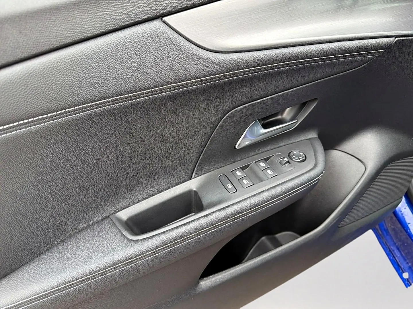 Détail de la porte avant gauche noire de l’Opel Mokka 1.2 turbo 136 édition avec commandes de vitres et poignée chromée.