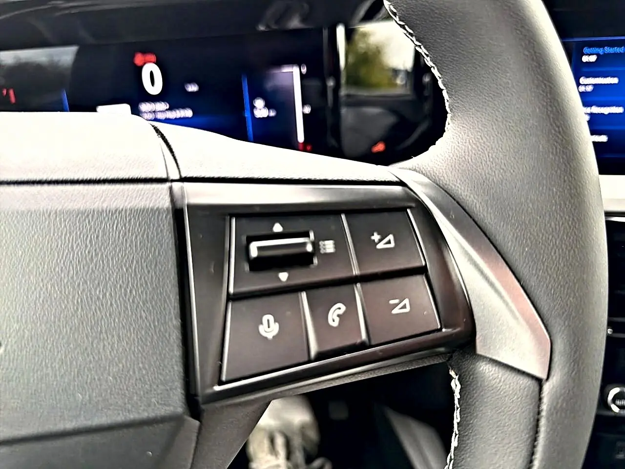 Gros plan sur les commandes multifonctions à gauche du volant gris de l'Opel Mokka 2025, avec écran digital en arrière-plan.