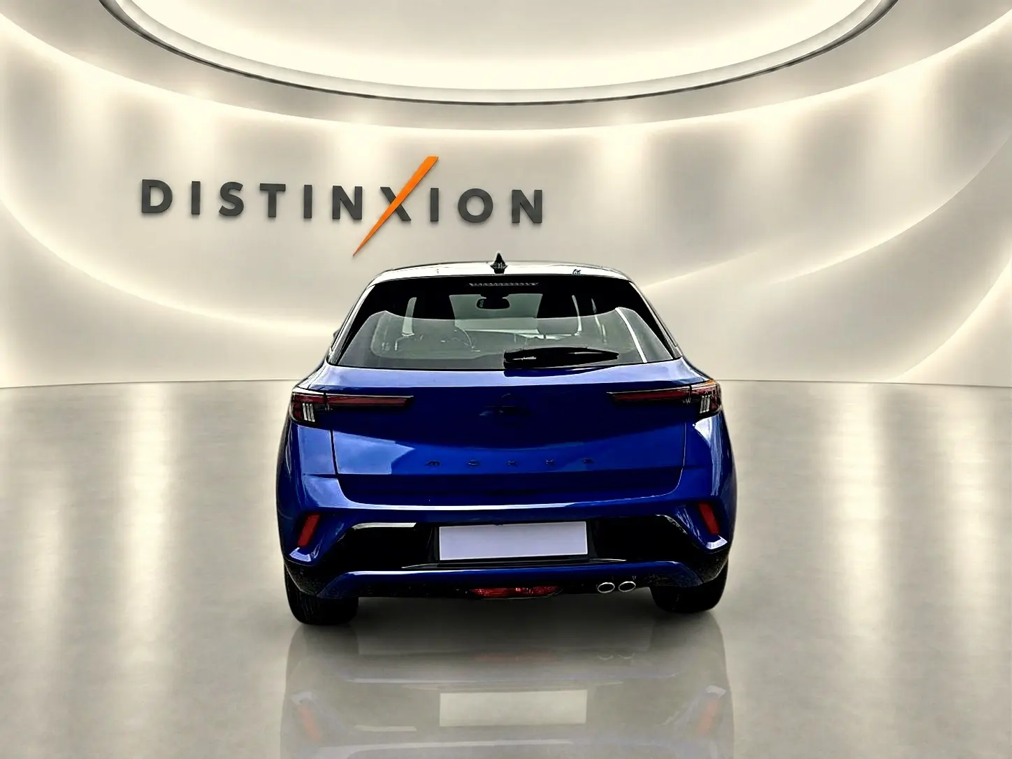 Vue arrière d'un Opel Mokka bleu 2025 dans un showroom avec double sortie d'échappement et feux LED fins.