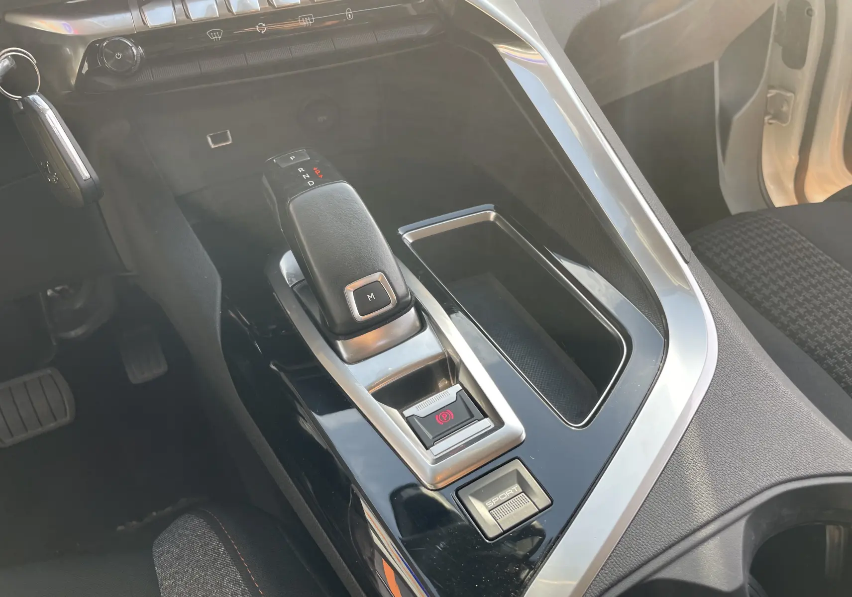 Vue rapprochée de la console centrale noire et argentée du Peugeot 3008 blanc, montrant le levier de vitesse automatique et bouton sport.
