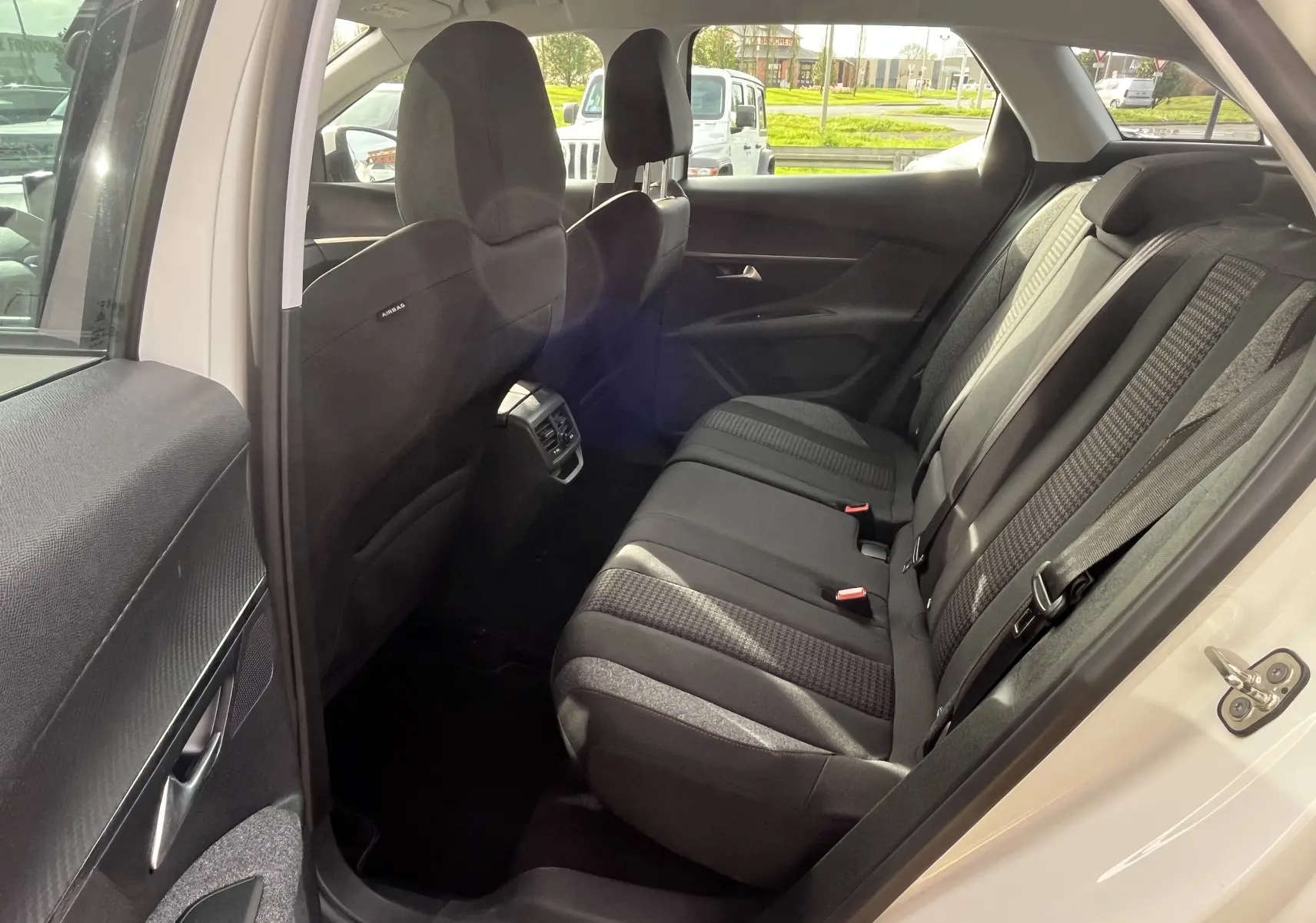 Vue intérieure côté droit des sièges arrière noirs du Peugeot 3008 blanc, avec ceintures et aérateurs centraux visibles.