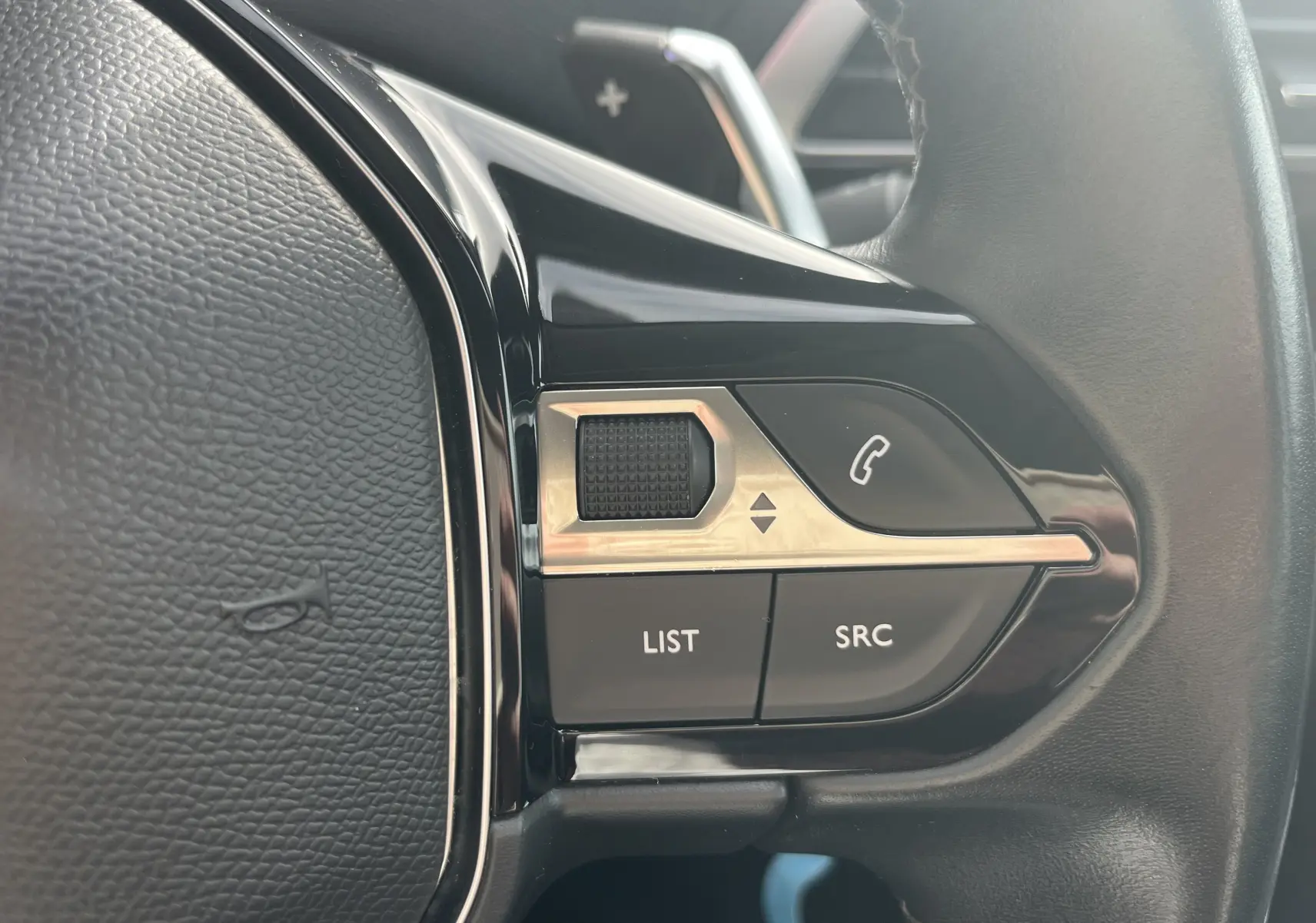 Gros plan sur les commandes multifonctions noires et chromées du volant du Peugeot 3008 blanc, version 2018.