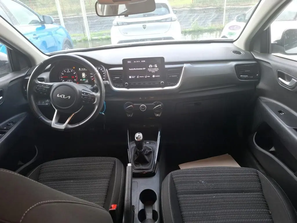 Vue intérieure avant du Kia Stonic blanc 2022, montrant le volant multifonction, écran central et levier de vitesses manuel.