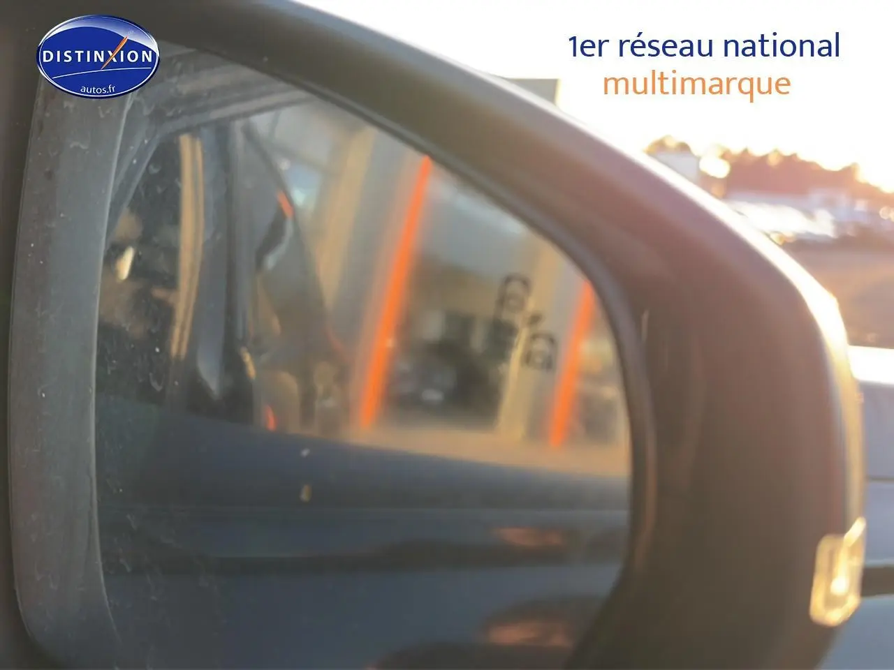 Rétroviseur extérieur droit noir du DS7 1.5 BlueHDi 130 Performance Line avec reflet flou d’un bâtiment au coucher du soleil.