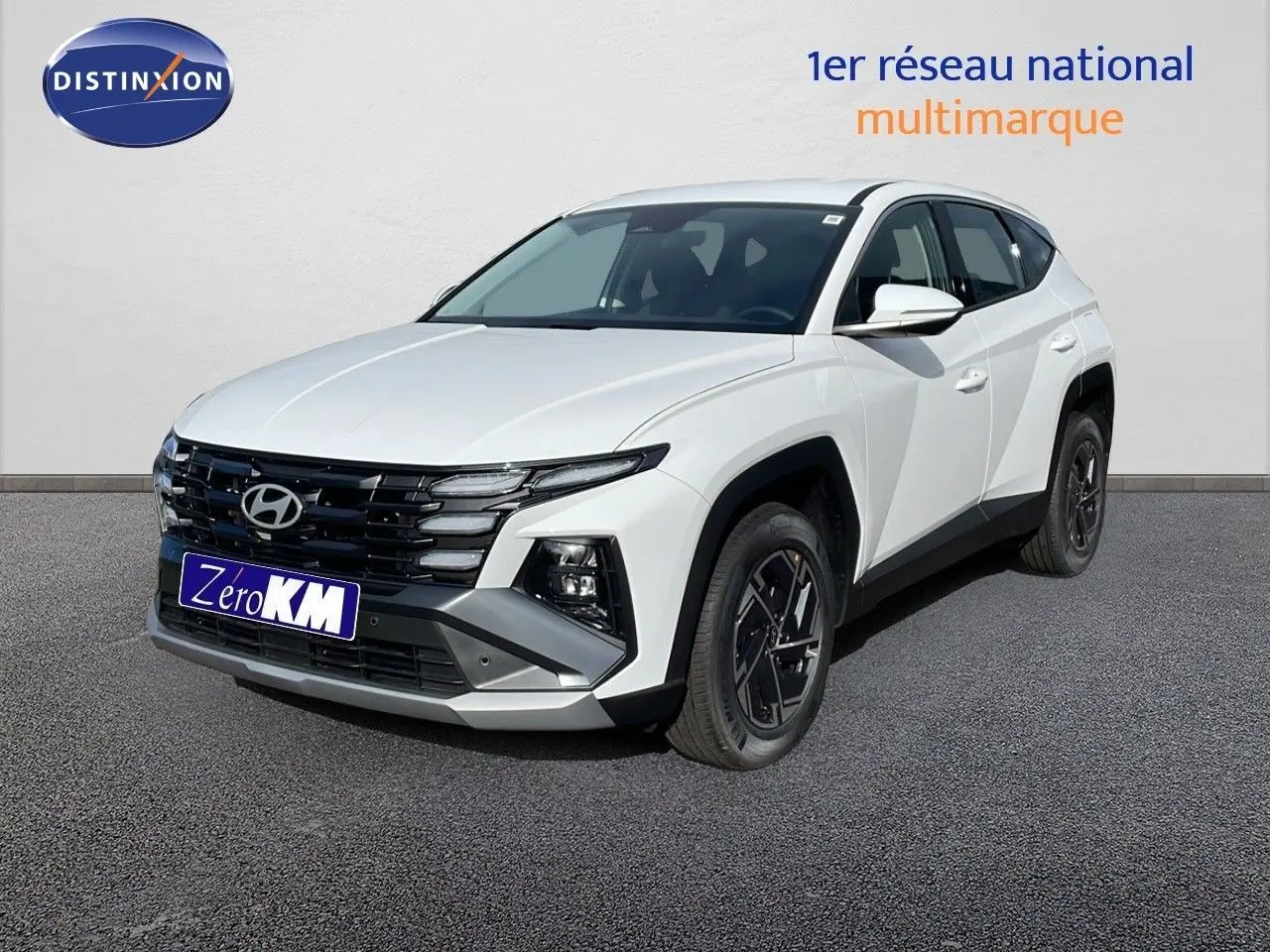 Hyundai Tucson blanc atlas en 3/4 avant droit, avec calandre noire et jantes alliage bicolores.