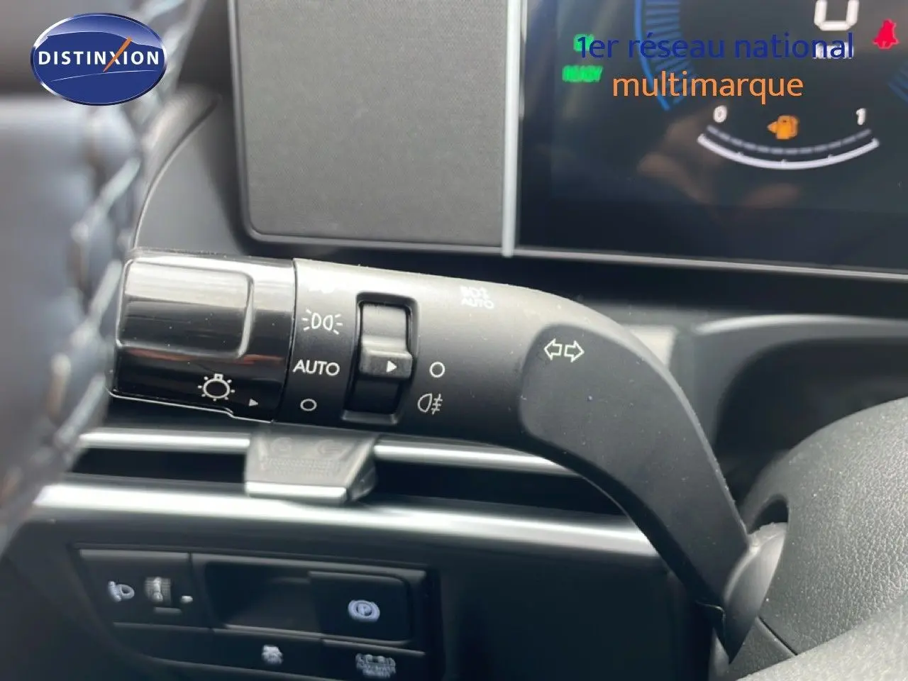 Gros plan sur la commande de clignotants et feux du Hyundai Tucson blanc Atlas, intérieur noir, tableau de bord digital.
