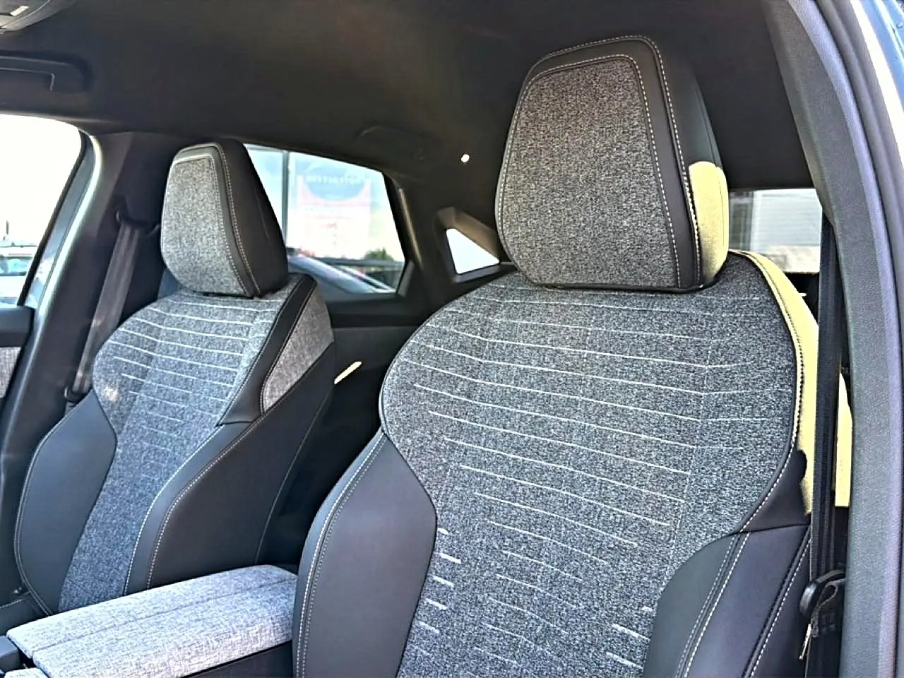 Vue rapprochée des sièges avant en tissu gris et cuir noir du Peugeot 3008 1.2 Hybrid 145 Allure 2025.