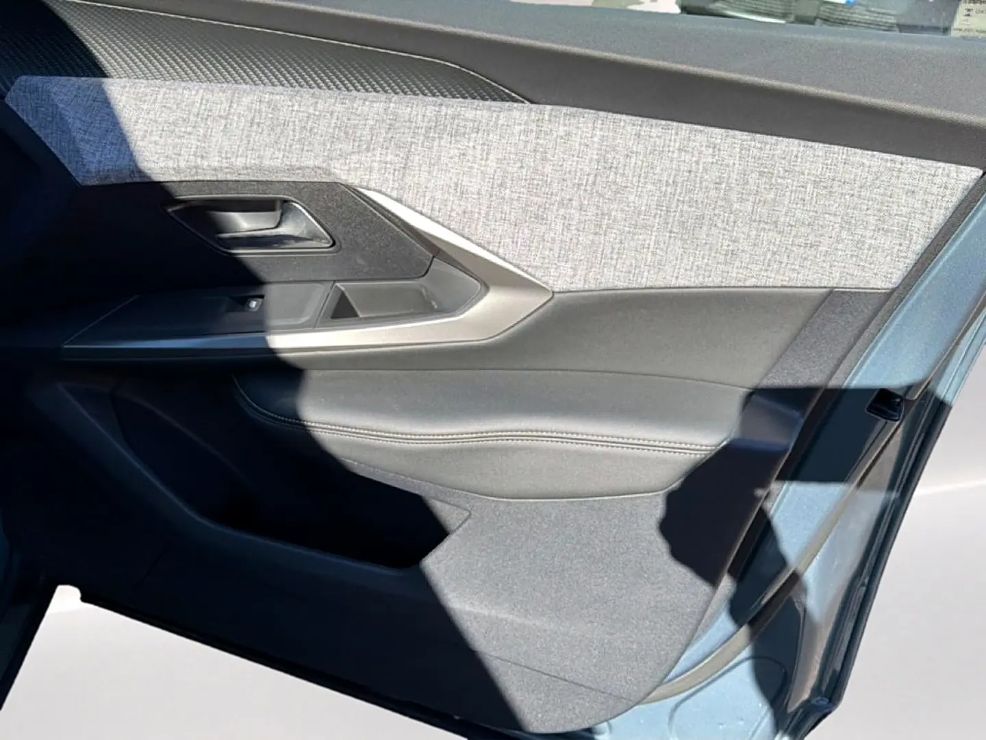 Vue rapprochée de la porte avant gauche du Peugeot 3008 2025 bleu Ingara, avec habillage tissu et cuir gris.